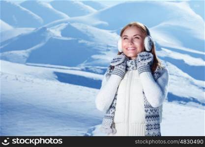 Portrait of happy cute woman standing outdoors and wearing beautiful warm knitted set, spending winter holidays in the snowy mountains