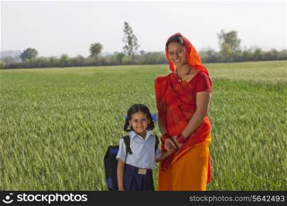 Portrait of happy daughter and mother standing together with field in background