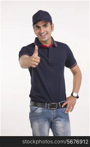 Portrait of happy delivery man gesturing thumbs up against white background