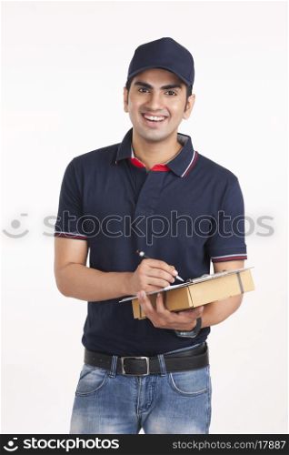 Portrait of happy delivery man with package and clipboard against white background