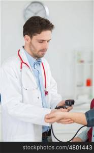 portrait of happy doctor checking patients blood pressure in clinic