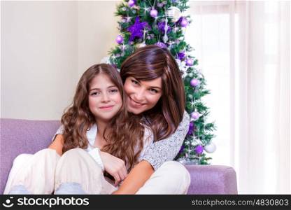 Portrait of happy family at home in New Year eve, Christmas tree decorated with purple baubles, teen girl with mother, friendship and love concept