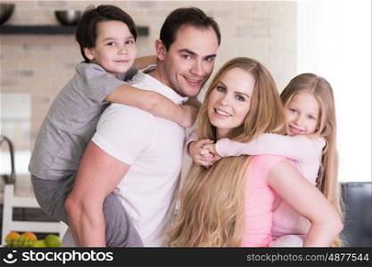 Portrait of happy family, father and mother giving boy and girl piggy back ride at home