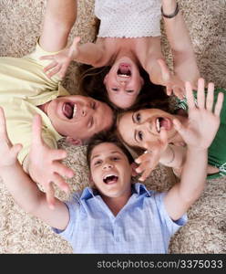 Portrait of happy family lying on carpet with their heads close together and shouting