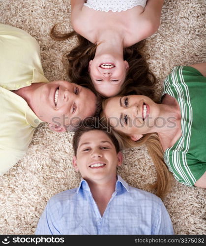 Portrait of happy family lying on carpet with their heads close together and smiling.