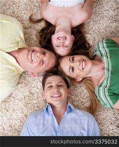 Portrait of happy family lying on carpet with their heads close together and smiling.