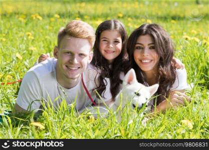 Portrait of happy family on grass field, Two parents and daughter lay down on lawn with dog puppy husky. Portrait of happy with dog