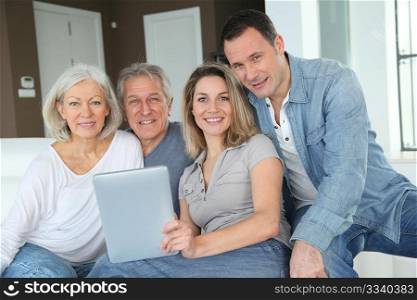 Portrait of happy family sitting in sofa with electronic tablet