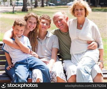 portrait of happy family sitting on park bench.