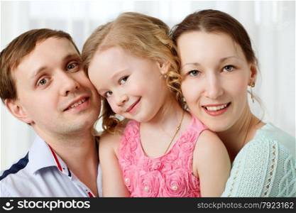 Portrait of happy family. Young parents with cute little daughter. Girl looking shy. Happy young parents and little daughter