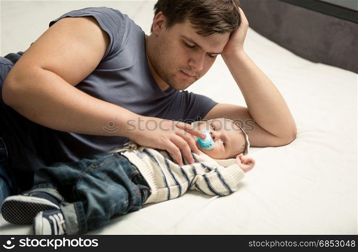 Portrait of happy father and baby boy lying on bed