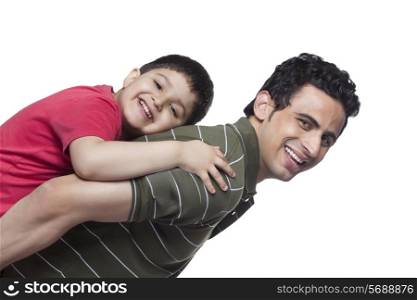 Portrait of happy father giving piggyback ride to son over white background