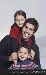 Portrait of happy father with children over grey background