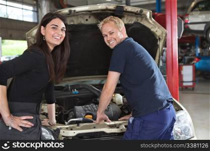 Portrait of happy female customer and mechanic in garage