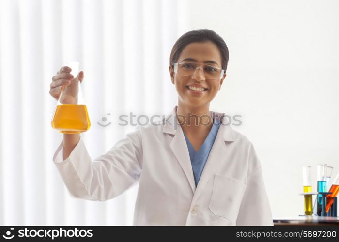 Portrait of happy female scientist holding flask in lab