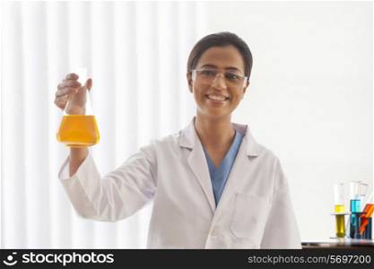Portrait of happy female scientist holding flask in lab