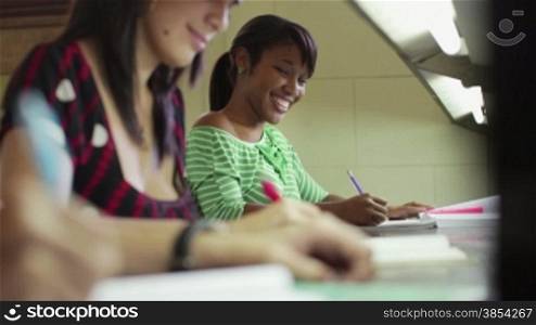 Portrait of happy female student writing and preparing test, pretty black girl smiling at camera in college library