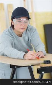 portrait of happy female woodworker drafting new project at workshop