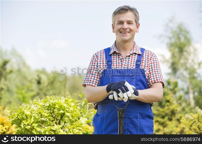 Portrait of happy gardener holding spade in plant nursery