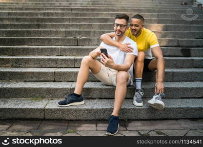 Portrait of happy gay couple spending time together and taking a selfie with mobile phone. Lgbt and love concept.