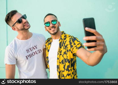 Portrait of happy gay couple spending time together and taking a selfie with mobile phone. Lgbt and love concept.