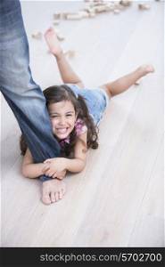 Portrait of happy girl being dragged by father on hardwood floor