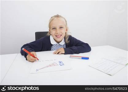 Portrait of happy girl drawing on paper at table