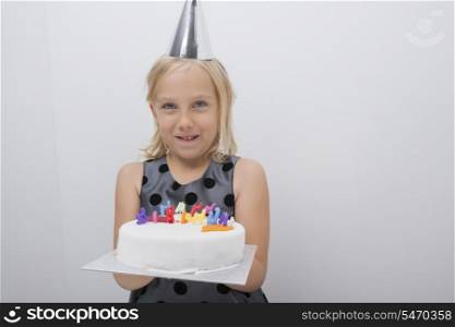Portrait of happy girl holding birthday cake at home