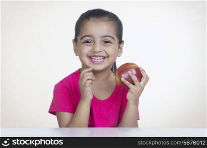 Portrait of happy girl holding fresh apple against colored background