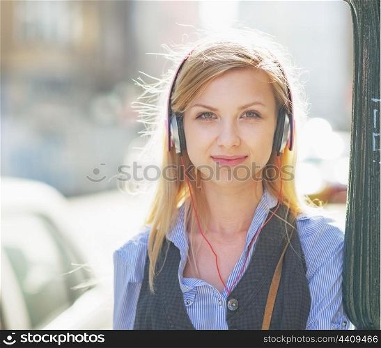 Portrait of happy girl listening music on city street