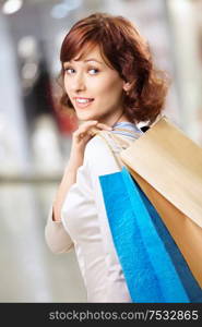 Portrait of happy girl standing in a half-turn with packages in shop