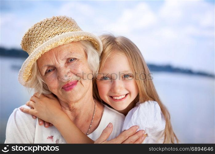 Portrait of Happy Grandmother and Granddaughter looking at the Camera at the Sunny Summer Day