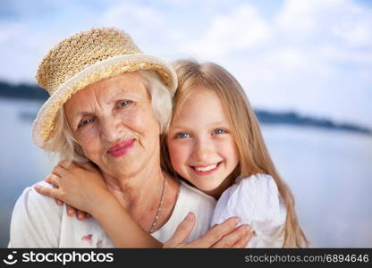 Portrait of Happy Grandmother and Granddaughter looking at the Camera at the Sunny Summer Day
