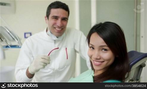 Portrait of happy hispanic man working as dentist in dental studio and young asian woman smiling, people and oral hygiene, health care in hospital. 7of19