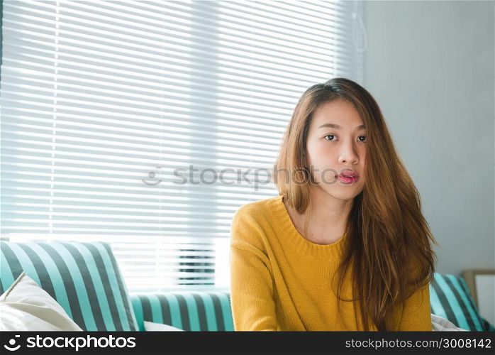Portrait of happy home owner asian woman with perfect teeth smiling sitting on sofa in the living room in house interior. Relaxing asian woman sitting comfortable in sofa lounge chair smiling happy.