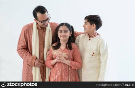 Portrait of happy Indian family handsome teenage son, little daughter and father embracing standing and talking, wearing traditional clothing. Family love bonding concept. White background