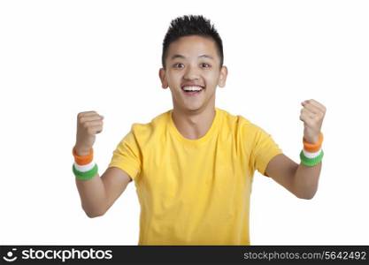 Portrait of happy Indian young boy cheering with clenched fists over white background