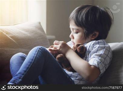 Portrait of happy kid sitting next to window playing with dog toys, Cute boy play with his soft ftoy, Positive child relaxing at home. child stay at home during covid-19 lock down, Social Distancing