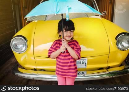 Portrait of Happy Kids with an Umbrella before Outing. Protecting Rain or Sunlight in Summer or Rainy Season Concept. Cute 3-4 Years Old Girl in Happiness Moment.Looking at Camera