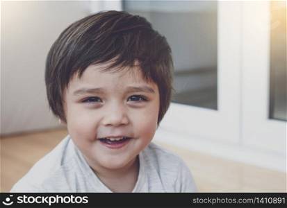 Portrait of happy little boy looking at camera with smiling face, Head shot Healthy child playing in kid room, Positive kid relaxing at home on weekend during spring or summer time