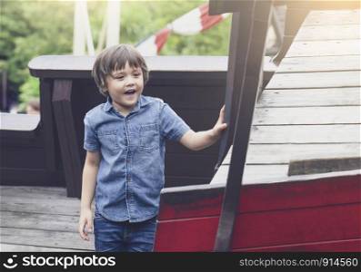 Portrait of happy little boy playing in the playground in the park, Kid with smiling face enjoy playing outdoor, Active child having fun playing in natural park on weekend.