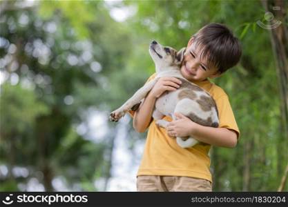Portrait of happy little boy playing with his adorable puppy.This toddler is so happy to play at the park with his favorite animal.