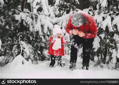 Portrait of happy little girl in red coat with dad having fun with snow in winter forest. girl playing with dad. Portrait of happy little girl in red coat with dad having fun with snow in winter forest. girl playing with dad.