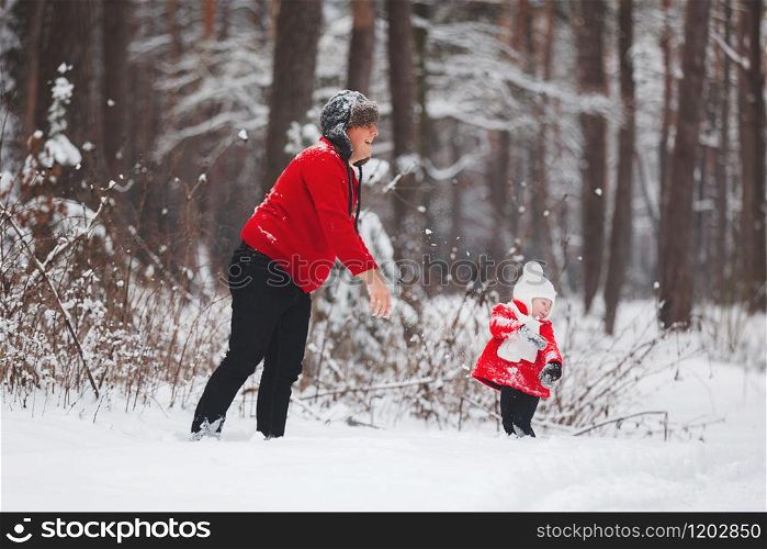 Portrait of happy little girl in red coat with dad having fun with snow in winter forest. girl playing with dad. Portrait of happy little girl in red coat with dad having fun with snow in winter forest. girl playing with dad.
