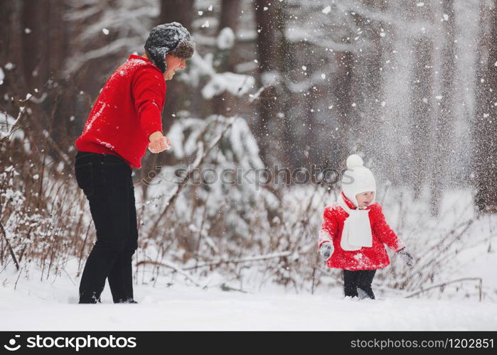 Portrait of happy little girl in red coat with dad having fun with snow in winter forest. girl playing with dad. Portrait of happy little girl in red coat with dad having fun with snow in winter forest. girl playing with dad.