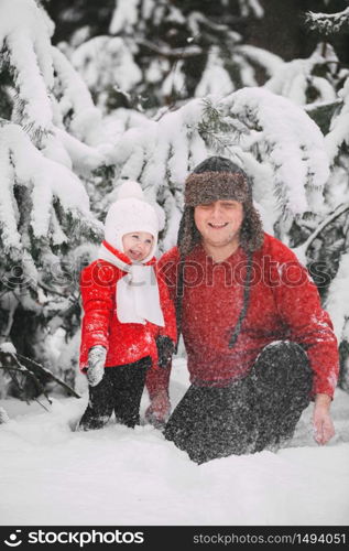 Portrait of happy little girl in red coat with dad having fun with snow in winter forest. girl playing with dad. Portrait of happy little girl in red coat with dad having fun with snow in winter forest. girl playing with dad.