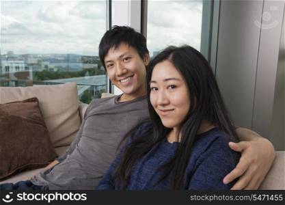 Portrait of happy loving couple sitting on sofa at home