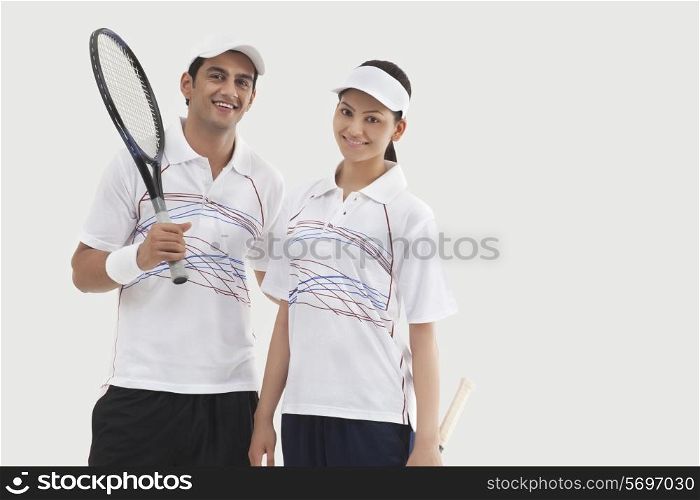 Portrait of happy male and female tennis players standing together isolated over white background