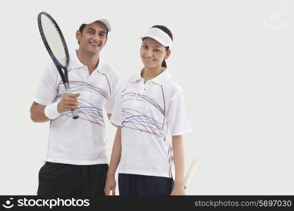 Portrait of happy male and female tennis players standing together isolated over white background