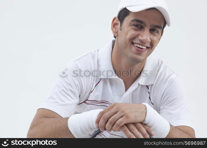 Portrait of happy male tennis player with racket isolated over gray background